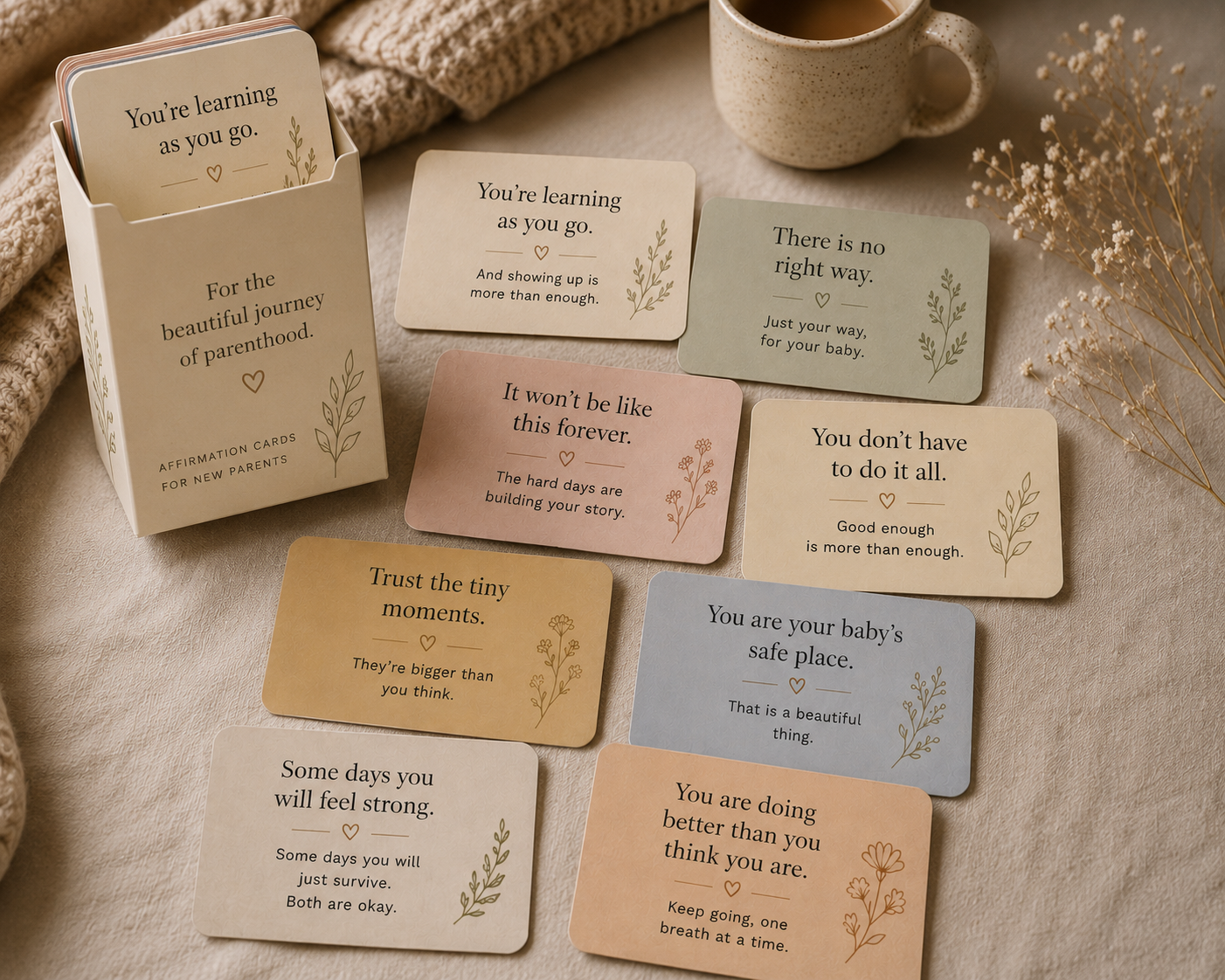 Affirmation cards for new parents fanned on a soft fabric surface with a cup of coffee